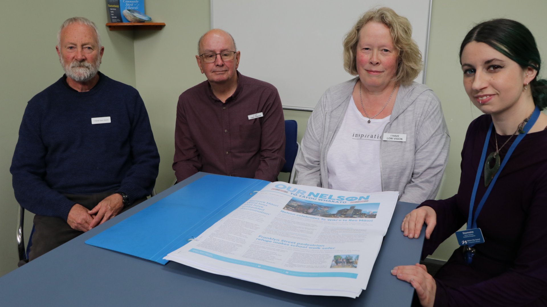 Photo: Mike Stevens, Rodger Curry, Karen Wilson from Blind Citizens NZ Nelson branch,<br />
read the large format Our Nelson, with Sharmaine Ford from Nelson Public Libraries.